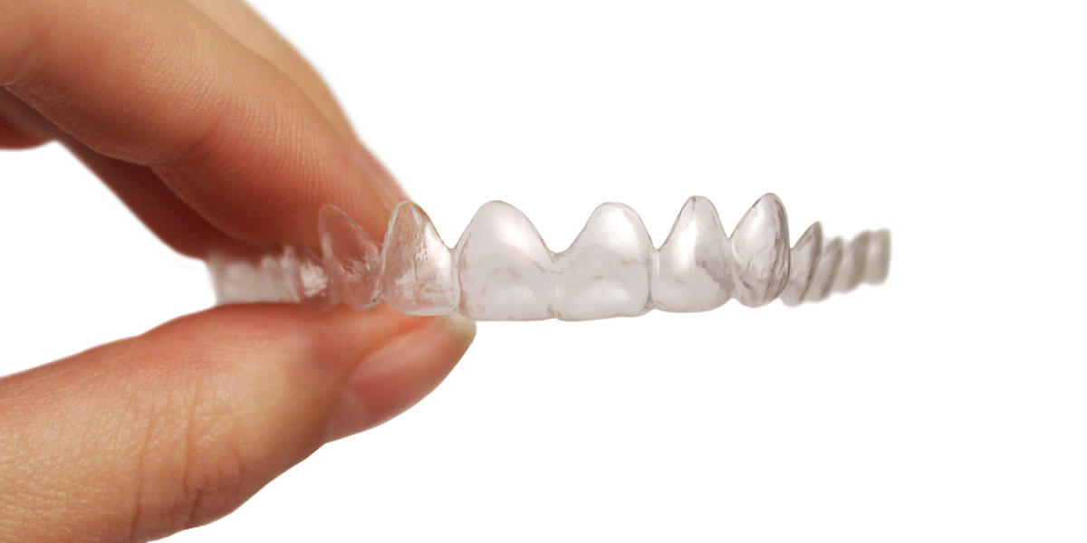 Person holding a clear invisalign aligner