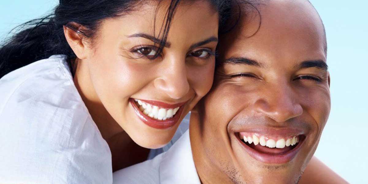 Woman and man smiling and laughing with full mouth restorations