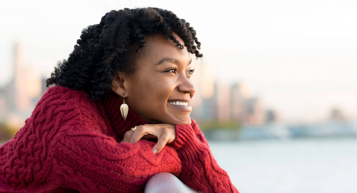 Woman leaning on a railing look out at the sunset